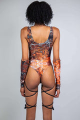 Back view of a model in a brown and orange marbled cut-out rave bodysuit with string details from Freedom Rave Wear.