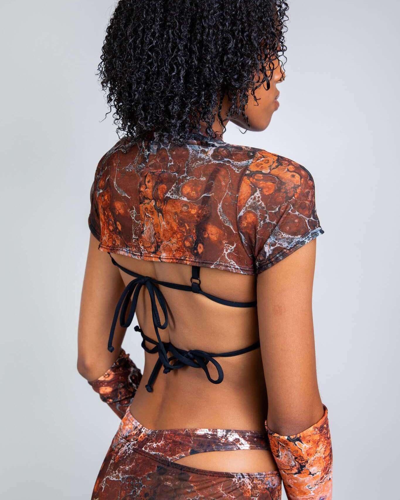 Model showcasing the Fossil Mesh Strobe Top with a marbled pattern, perfect for rave outfits, featuring a stylish open back.