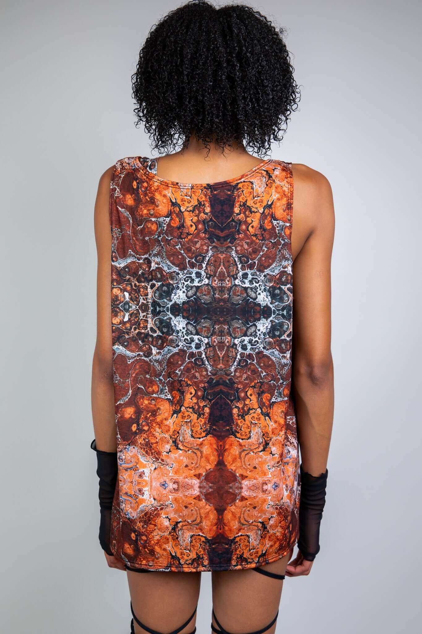 Back view of a model in a sleeveless, marbled brown and orange rave tank with abstract patterns, designed by Freedom Rave Wear.