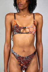 Model wearing Freedom Rave Wear's marble-patterned rave bikini with a cutout top and high-waisted bottoms in earthy brown and orange tones.