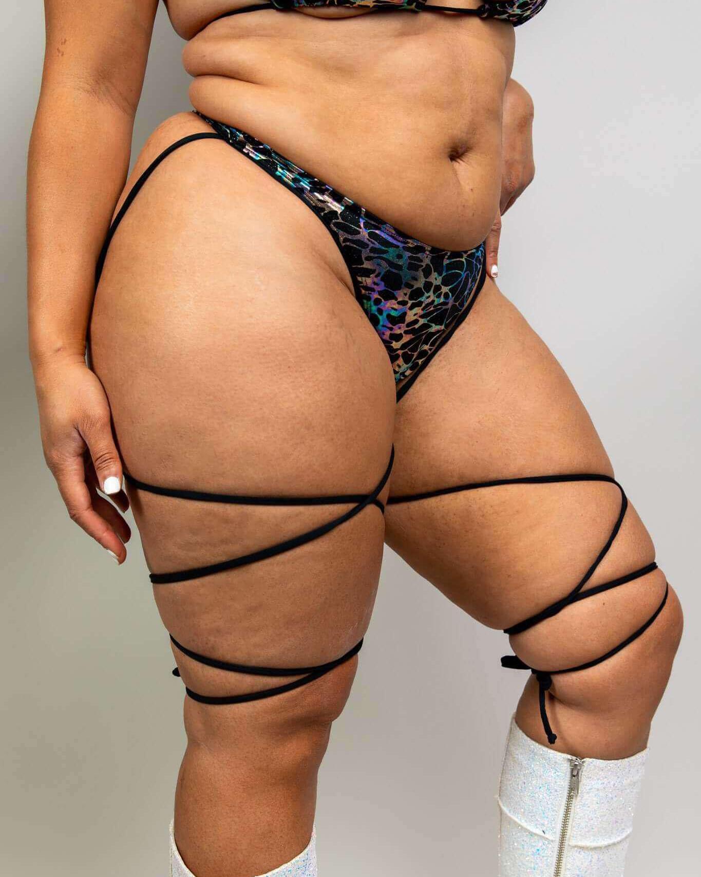 Galactica High Hip Strappy Bottoms in black and oil slick design showcased at a rave, featuring stylish leg straps.