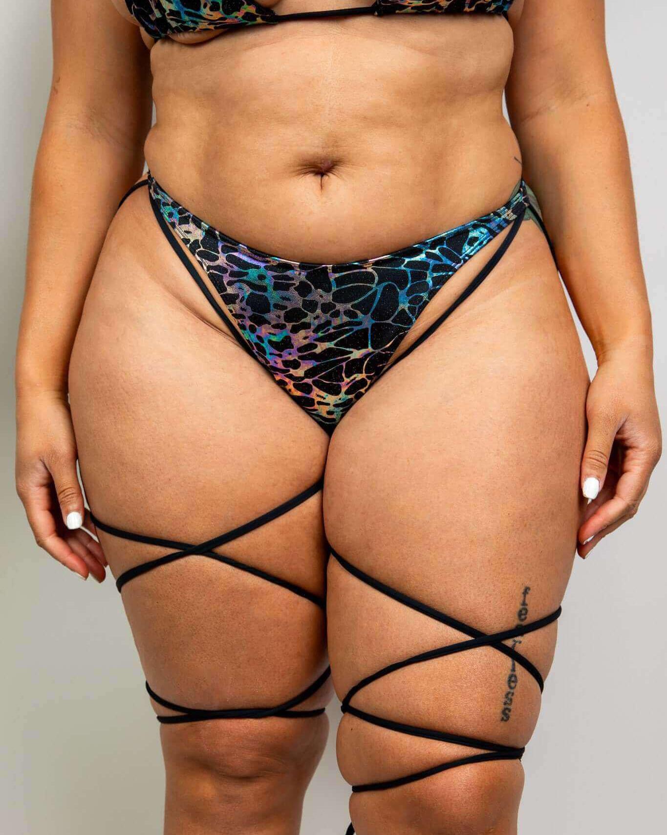 Galactica High Hip Strappy Bottoms in black and oil slick design, perfect for rave outfits, showcasing stylish leg straps.