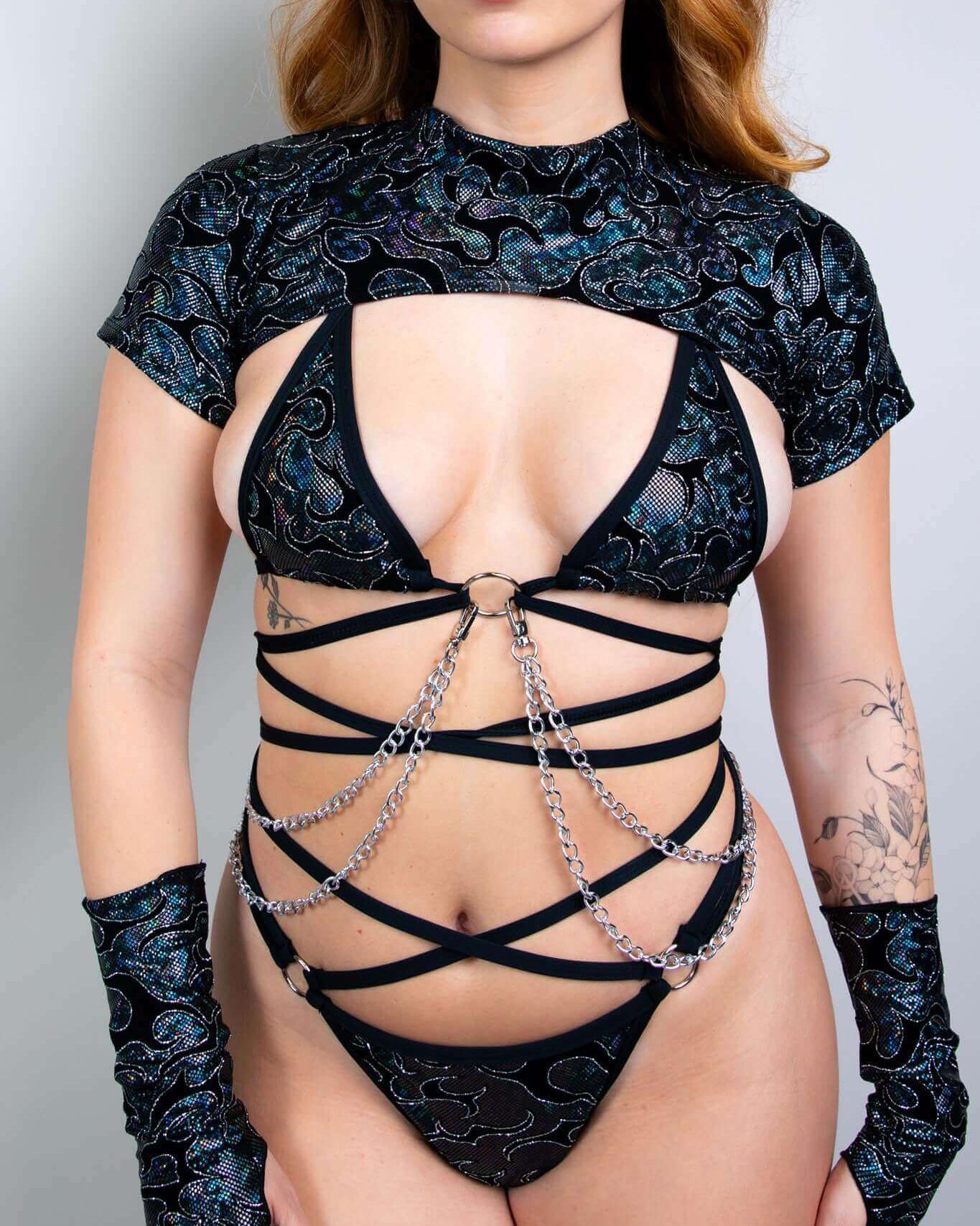 model wearing a black patterned strappy rave outfit with chains and gloves, perfect for bold festival fashion.