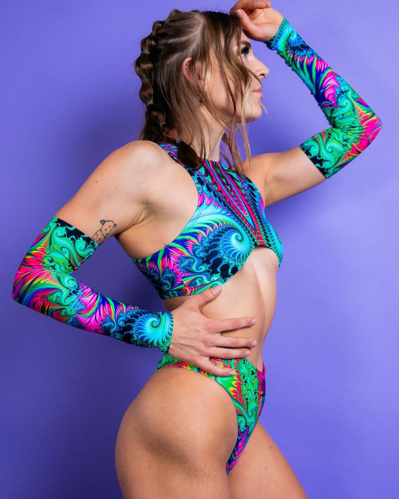 Model showcasing vibrant Hypnotic Arm Sleeves, complementing a colorful rave outfit against a purple background.