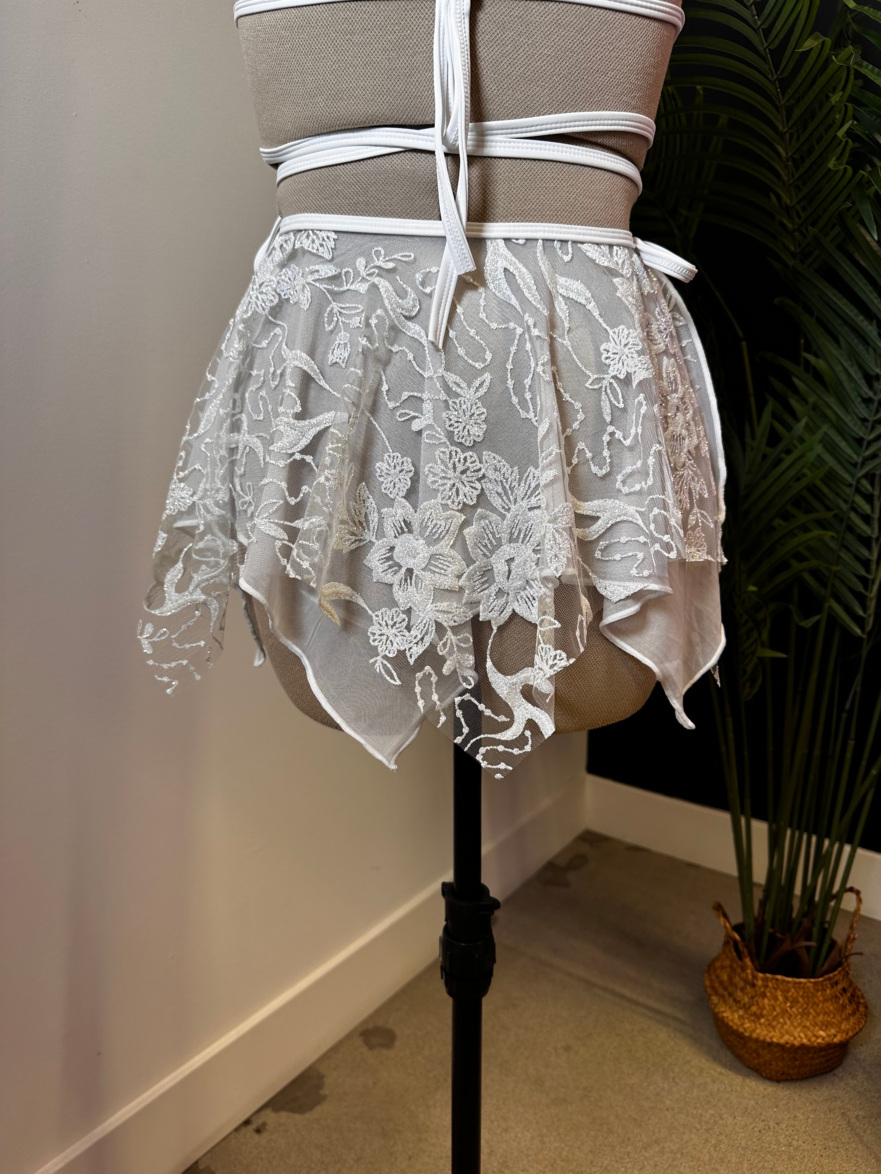 Seraphina Fairy Skirt in white, back view, featuring layered lace with asymmetrical hem and tie waist, ideal for ethereal rave fashion and festival wear.