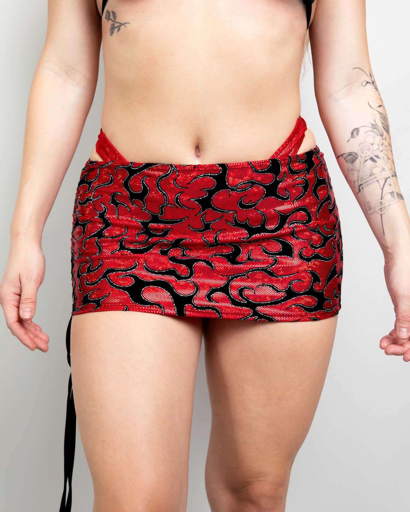 Model wearing the Inferno Cinch Skirt with adjustable ties in red and black flame pattern, perfect for rave outfits.