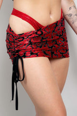 Model wearing the Inferno Cinch Skirt in red with adjustable ties, showcasing its ruched design for rave outfits.