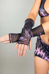 A photo of a woman's hands, wearing black mesh gloves with purple tattoo designs.