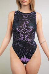 An up close photo of a woman wearing a black mesh bodysuit with a high neckline and purple tattoo like designs.