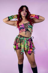 Model wearing a vibrant neon lace-up top and a colorful fairy skirt, perfect for rave outfits and festival fashion.