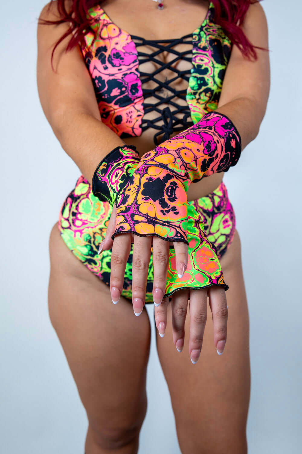 Model showcasing colorful Intensity Gloves, perfect for rave outfits with a vibrant skull design and thumb holes.