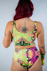 Back view of a model wearing a bright, UV reactive crop top and high-waisted bottom, perfect for rave outfits.