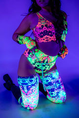 Woman wearing colorful UV reactive Intensity Leg Sleeves and matching rave outfit, showcasing vibrant patterns.