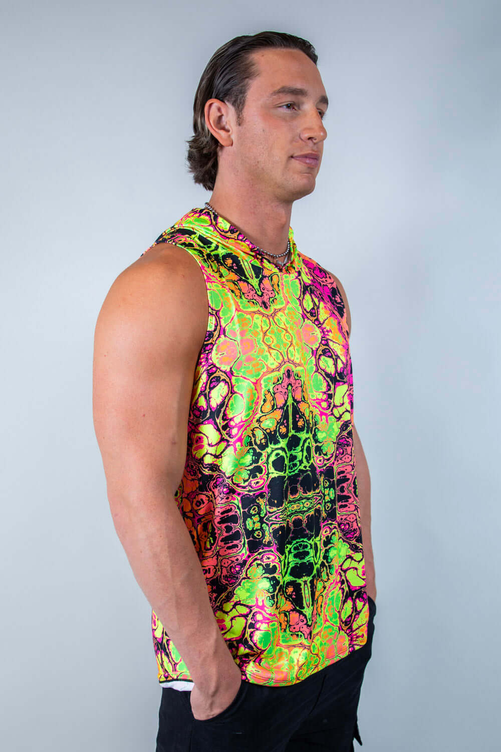 Model wearing a vibrant, neon-patterned Intensity men's tank top with hood, perfect for rave outfits.