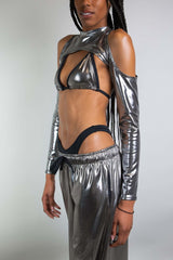 An up close photo of a woman wearing chrome pants with a matching bikini top and sleeves that have cutouts over the shoulders.