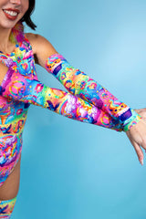 An up close photo of a woman's arms wearing rainbow sleeves with whimsical characters printed on them.