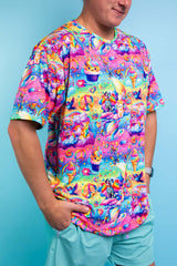 A man wearing a rainbow t shirt with whimsical characters on it and blue shorts.
