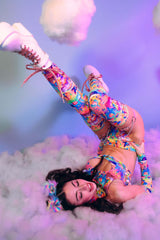 A girl lying on her back with her legs in the air wearing a rainbow outfit.