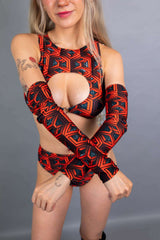  Model wearing Freedom Rave Wear's Labyrinth collection, featuring a red geometric design with a front cut-out, matching sleeves, and high-waist bottoms.