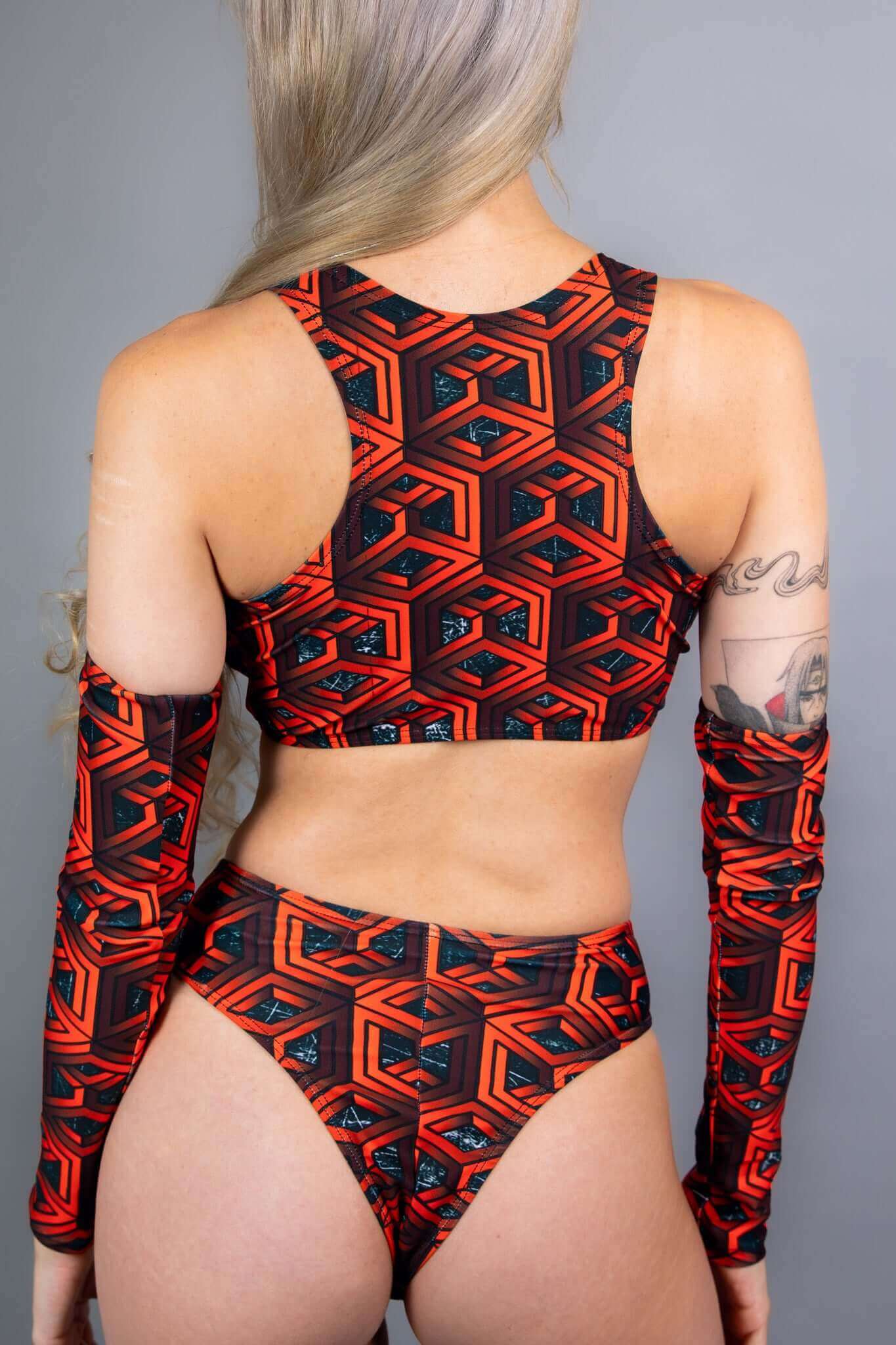  Model wearing Freedom Rave Wear's Labyrinth collection, showcasing the back view of a bold red geometric pattern with matching high-waist bottoms and sleeves.