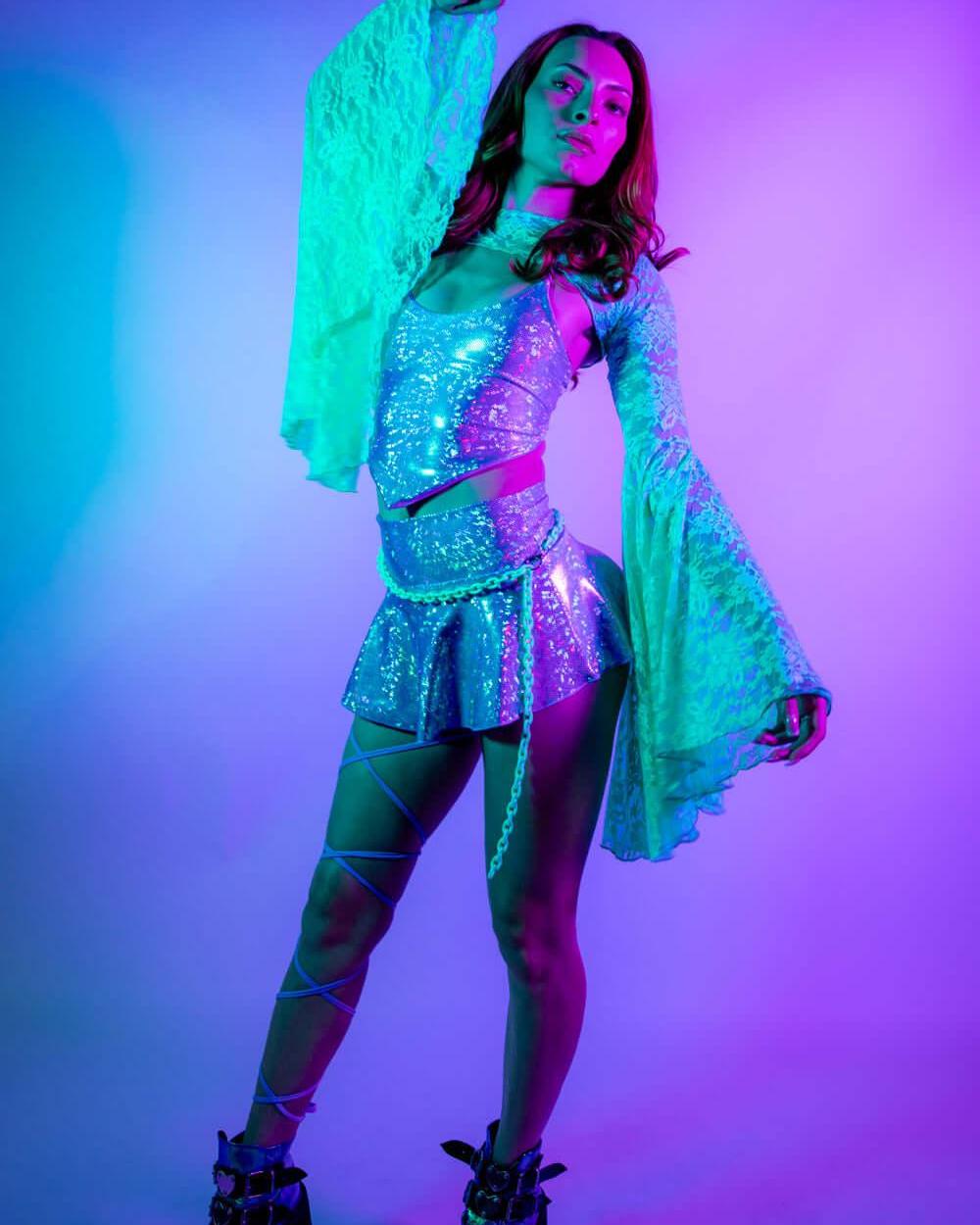 Model wearing a sparkling Lavender Holo V Top with flared sleeves, showcasing her rave outfit in a vibrant light.