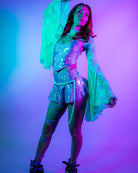 Model wearing a sparkling Lavender Holo V Top with flared sleeves, showcasing her rave outfit in a vibrant light.