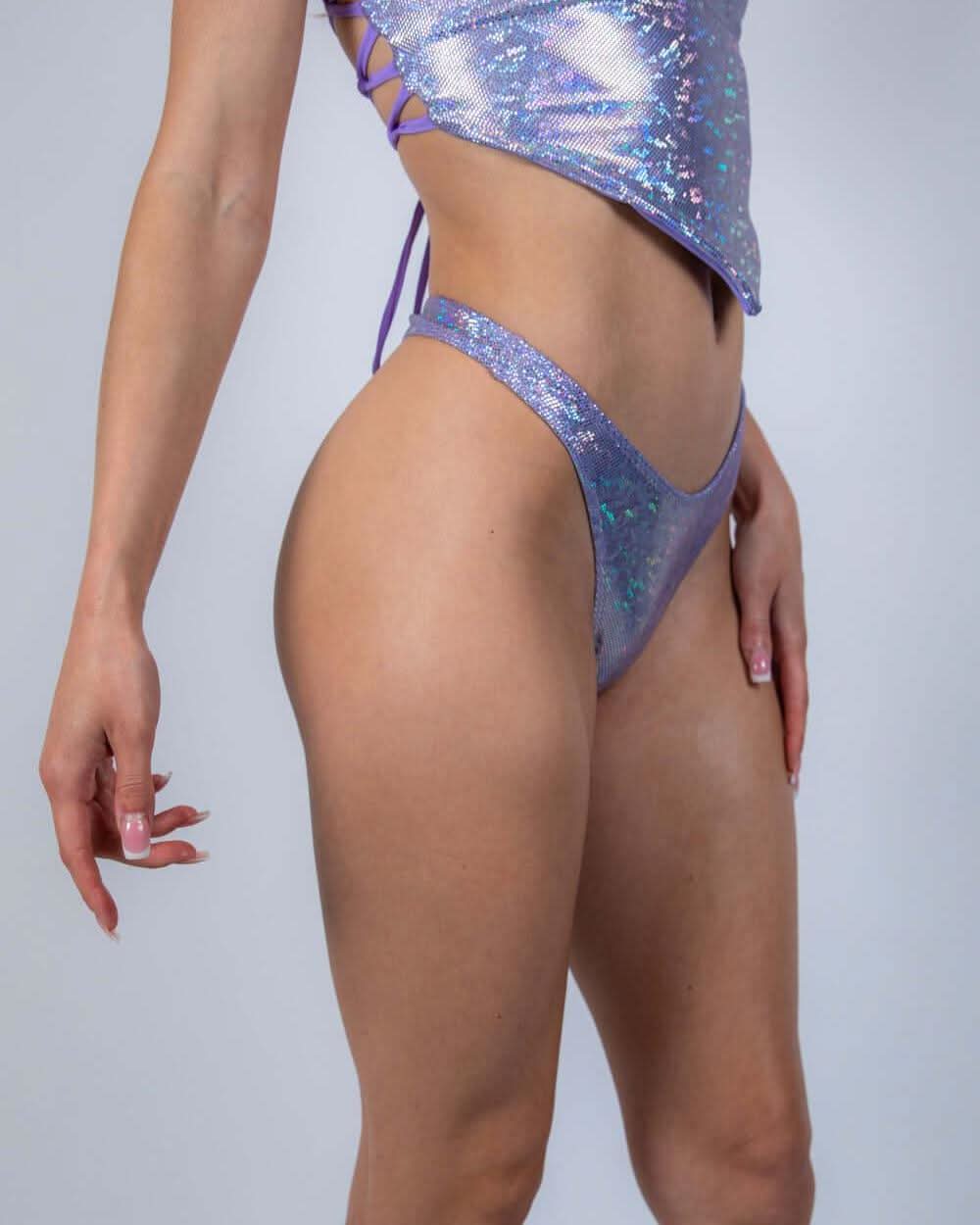 Lavender Holo Risk Bottoms – side view showing high-cut holographic bikini fit with cheeky thong back, modeled in lavender shimmer