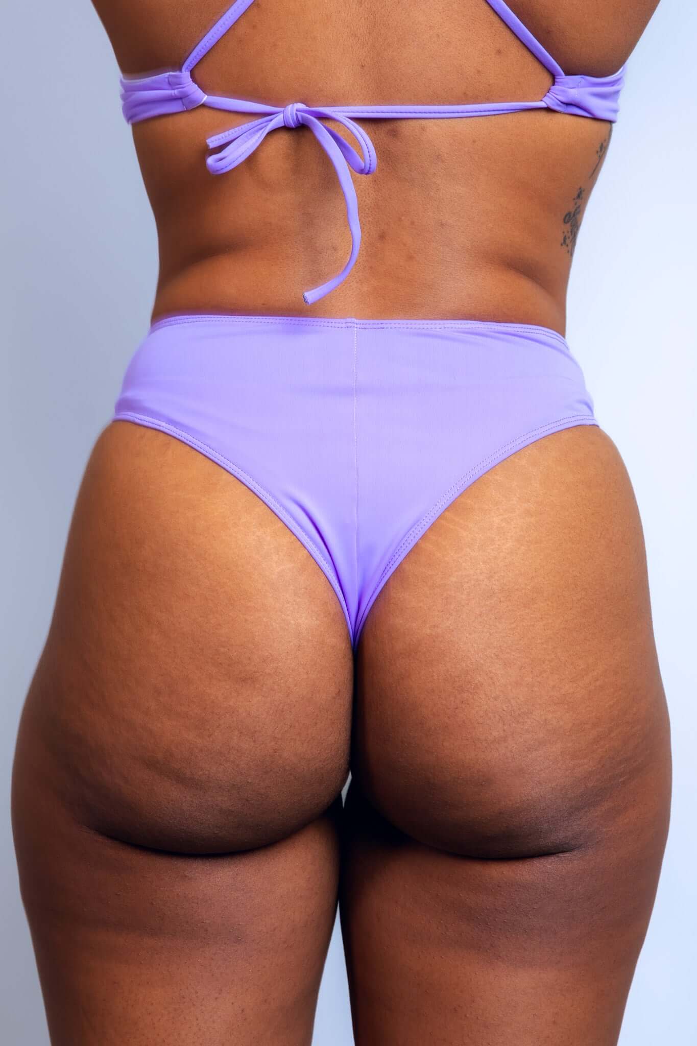 Close-up rear view of a model in Lavender Love high-waisted rave bottoms by Freedom Rave Wear.