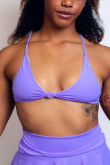 Close-up of a woman wearing a lavender Freedom Rave Wear halter top, showcasing a knot detail at the center and smooth fabric texture