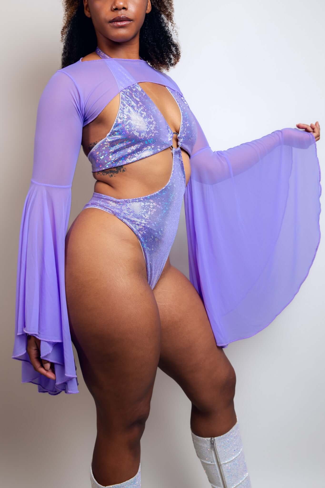 Mesmerizing lavender bodysuit adorned with glitter, showcasing keyhole cutouts and flowing bell sleeves, from Freedom Rave Wear.
