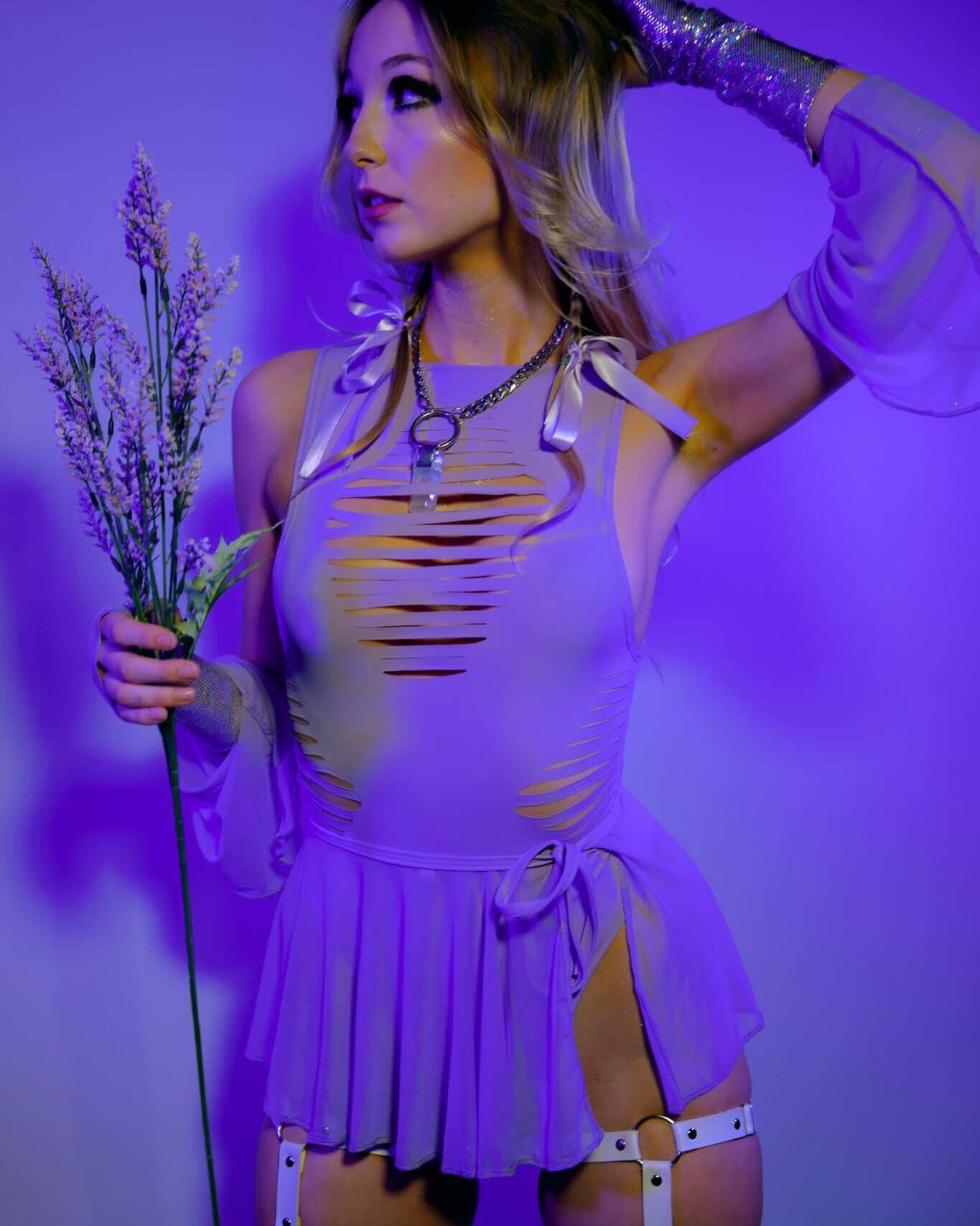 Model showcasing a lavender cut-out top and skirt ensemble, ideal for rave outfits, with stylish accessories and floral accent.