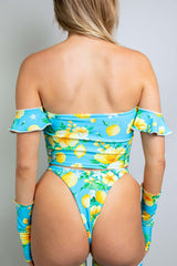 Model in a floral three-piece rave outfit from Freedom Rave Wear: off-shoulder top, high-waisted bottoms, and matching sleeves in blue and yellow.