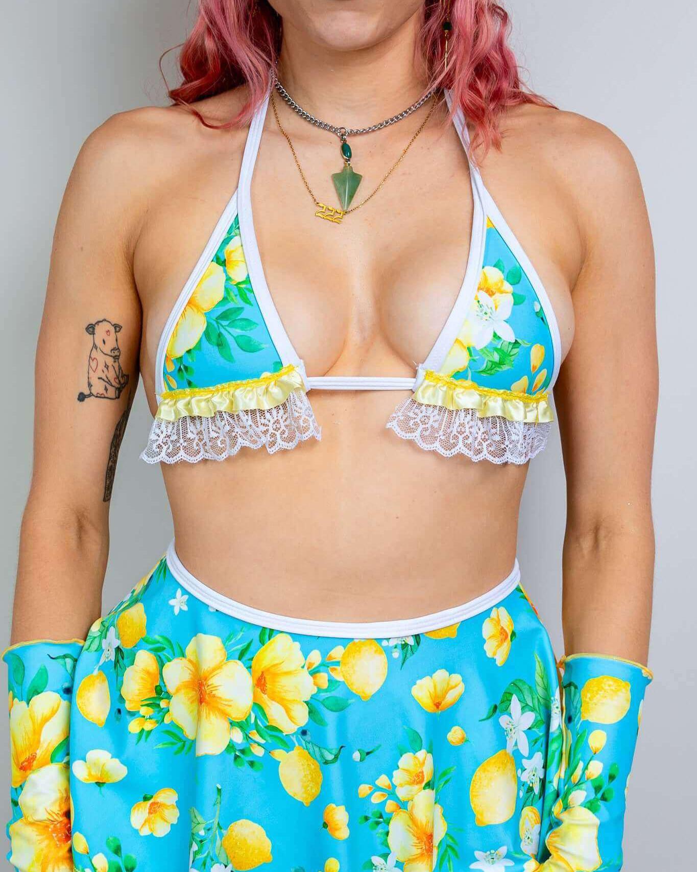 Model wearing Lemon Drop Bikini Top with Ruffles, featuring lemon prints and coquette ruffles, perfect for rave outfits.