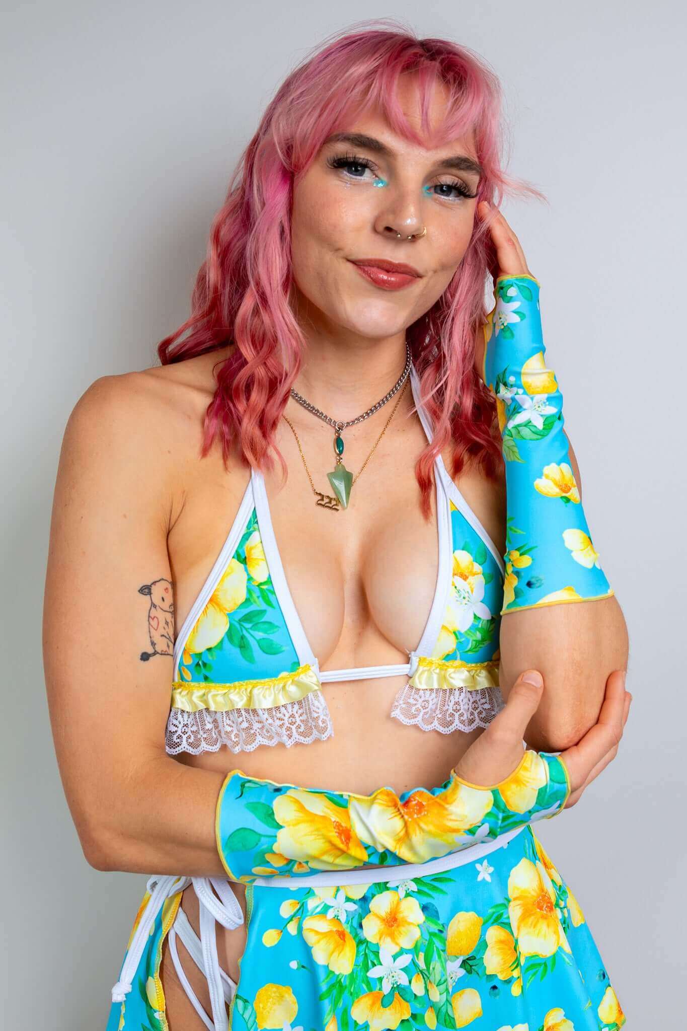 Model in a floral two-piece rave outfit from Freedom Rave Wear: triangle top with lace trim, high-waisted skirt, and matching sleeves.