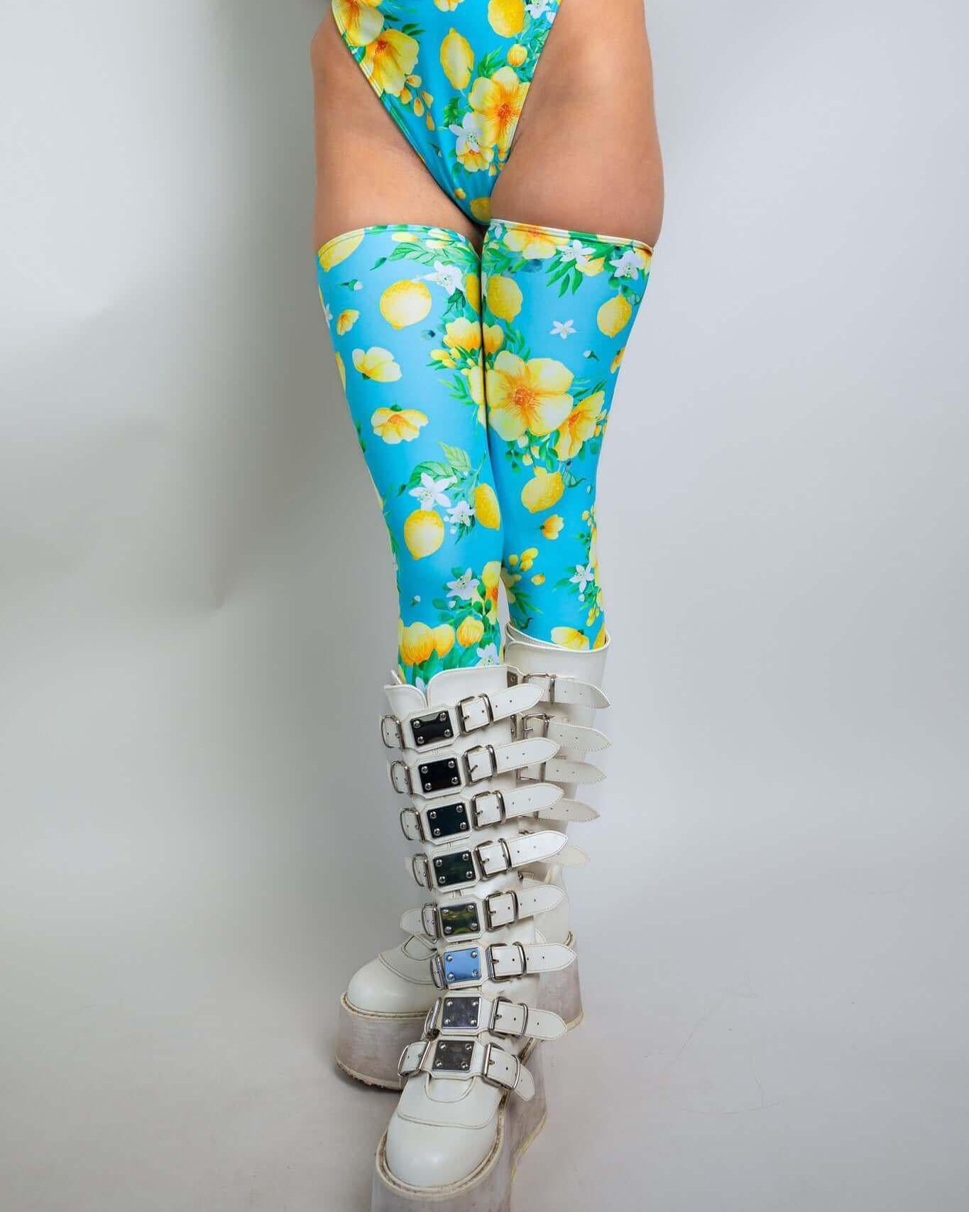 Model wearing Lemon Drop Leg Sleeves with floral print, paired with stylish white boots, perfect for rave outfits.