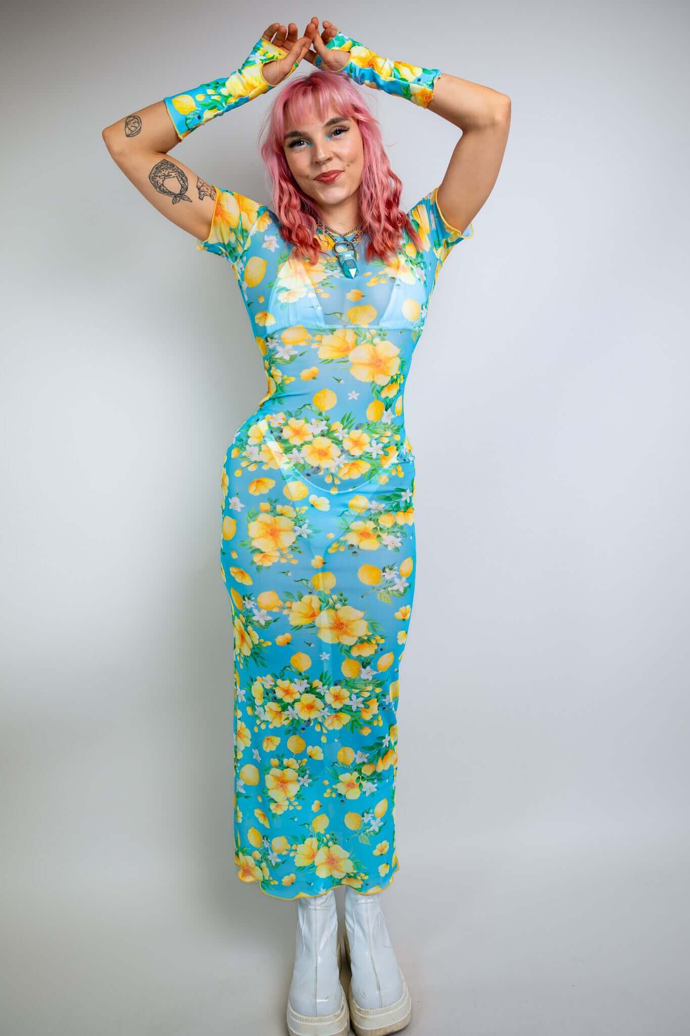 Model in a floral mesh dress from Freedom Rave Wear: blue and yellow full-length dress with matching sleeves, showcasing vibrant floral patterns.