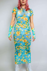 Model in a floral mesh dress from Freedom Rave Wear: blue and yellow full-length dress with matching sleeves, showcasing vibrant floral patterns.