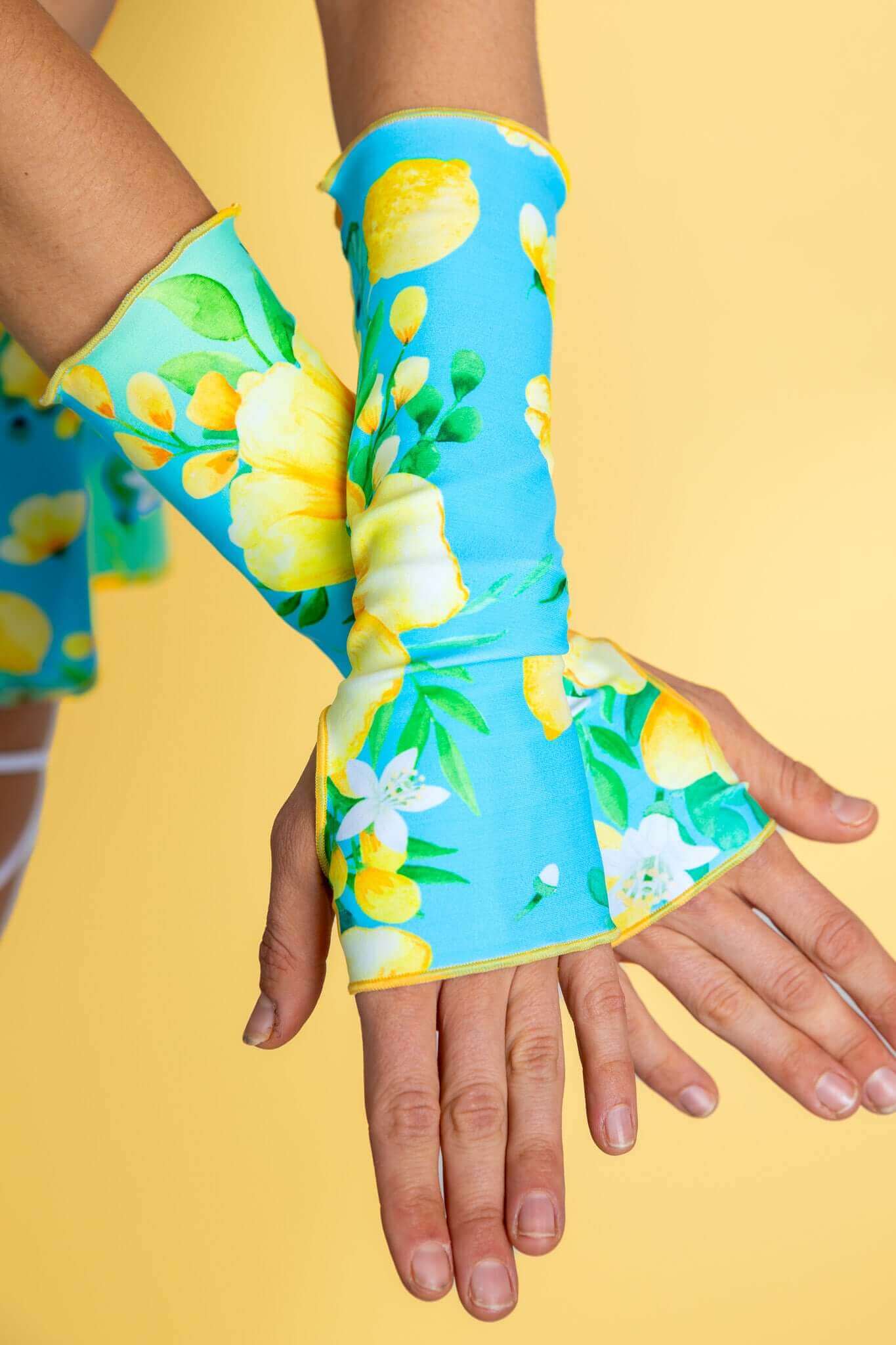 Close-up of Lemon Drop Gloves from Freedom Rave Wear, featuring a colorful blue and yellow print with a fingerless design that extends past the wrist.