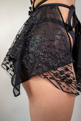 Side view of the Lilith Fairy Skirt, showcasing its flowy black sparkly fabric and layered design.