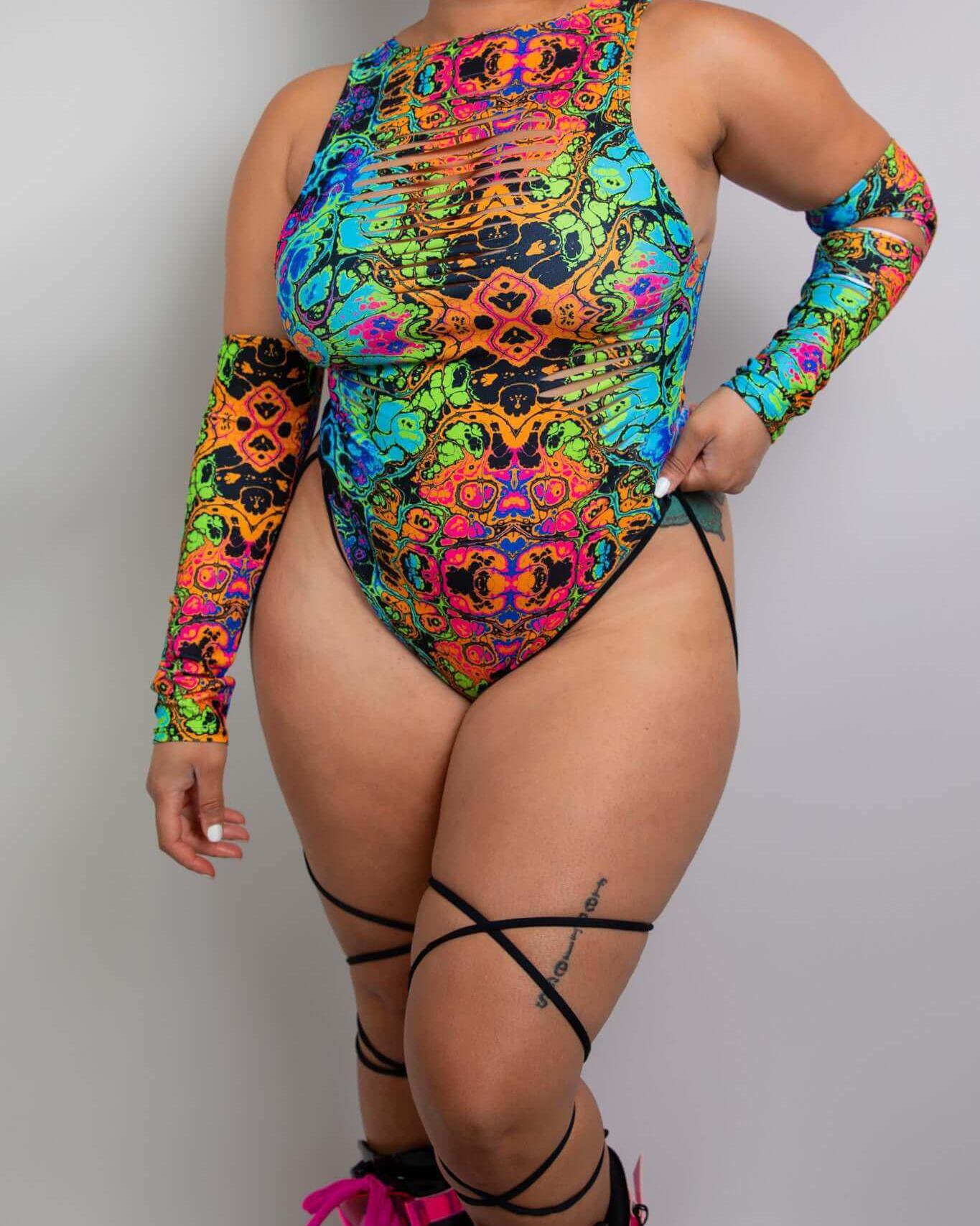 Woman in vibrant psychedelic rainbow bodysuit with leg straps, perfect for rave outfits and turning heads at parties.