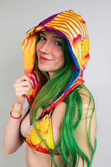 Playful close-up of a model in Freedom Rave Wear's colorful hood, paired with green hair and a sunny smile, evoking a vibrant festival spirit