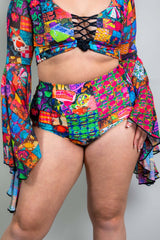 A woman wearing rainbow patchwork bikini bottoms and a matching crop top with flowy sleeves.