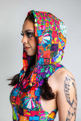 A girl with black swirly eye makeup wearing a rainbow patchwork hood and matching bodysuit. She is facing to the left.