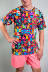 A man with his hand on his hip posing in a rainbow patchwork t-shirt and pink shorts.