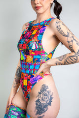 An up close photo of a girl wearing a rainbow patchwork bodysuit. She faces slightly to the left.