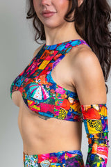 An up close photo of a woman wearing a rainbow patchwork crop top. She  is facing to the left.