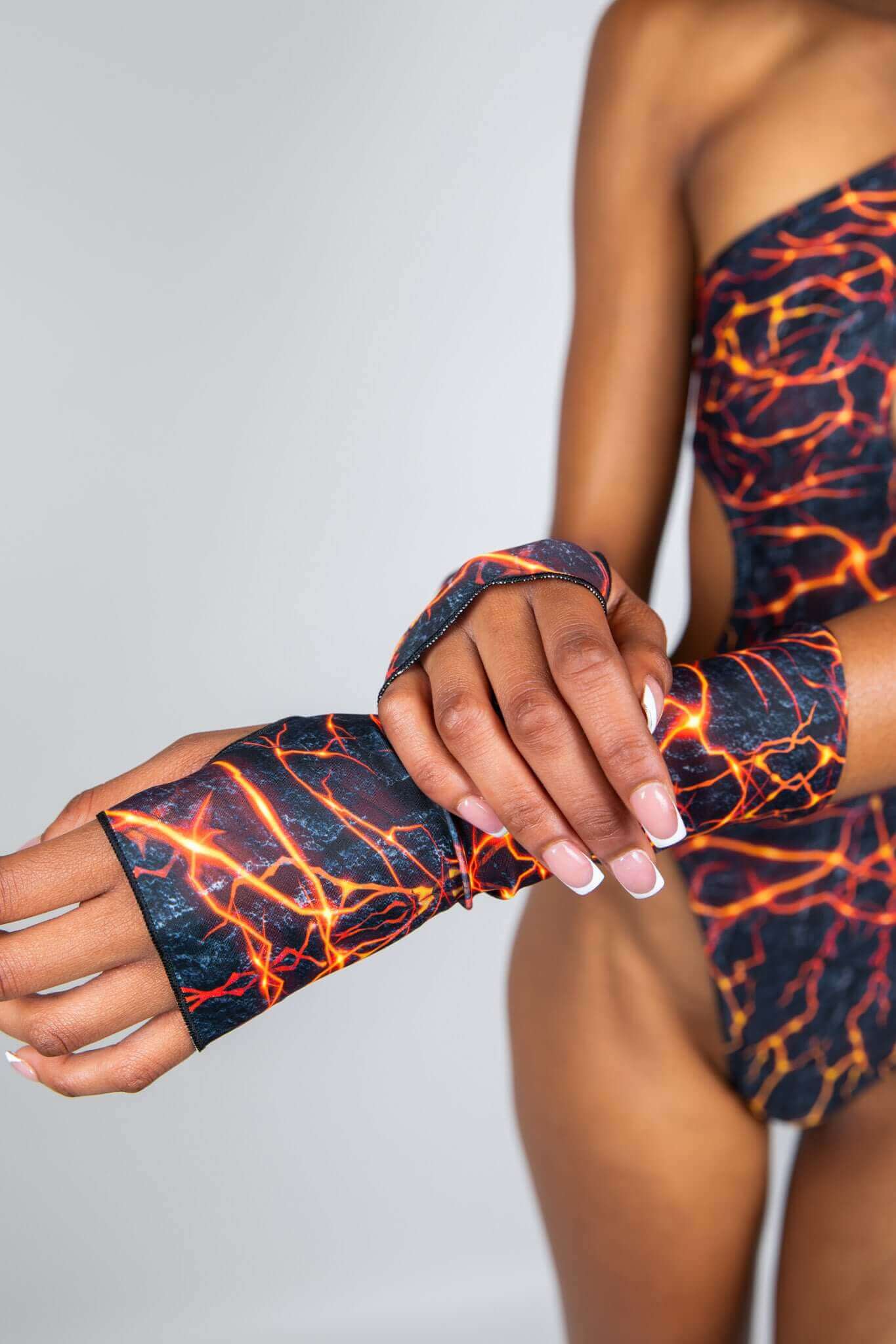 Close-up of model wearing lightning print fingerless gloves and matching bodysuit from Freedom Rave Wear, showcasing rave-inspired details.