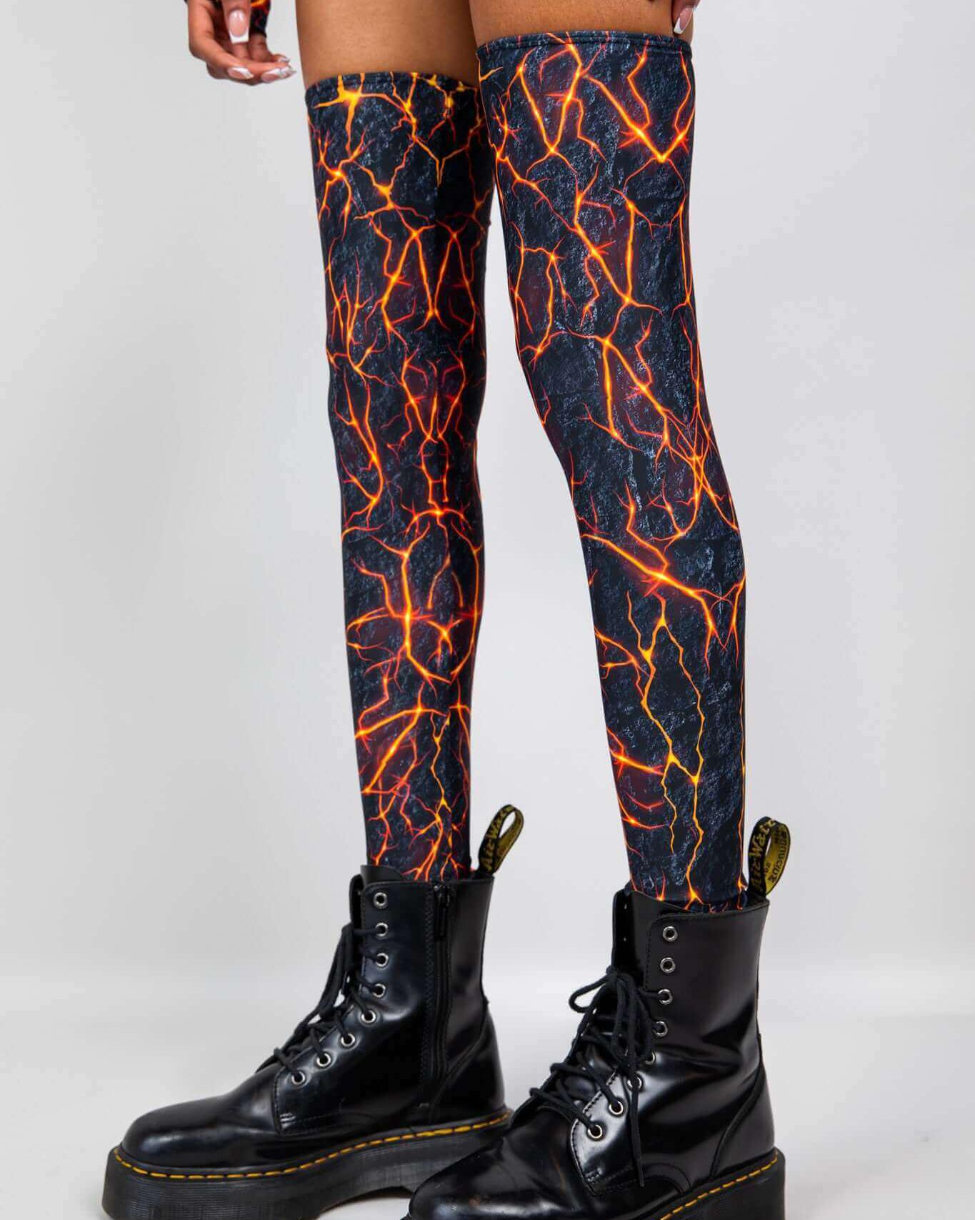 Magma Leg Sleeves in fiery lava design, paired with chunky black combat boots, perfect for rave outfits.