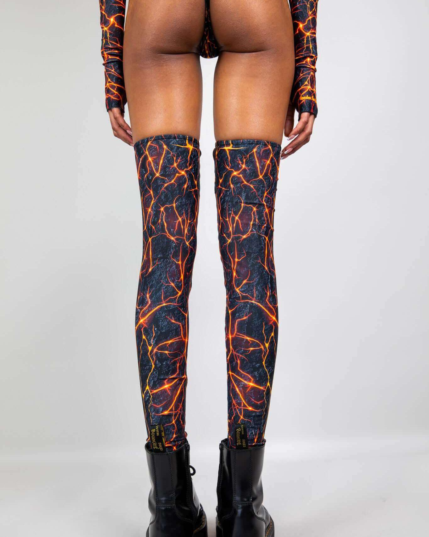 Model wearing Magma Leg Sleeves, thigh-high leg warmers with a fiery lava pattern, perfect for rave outfits.