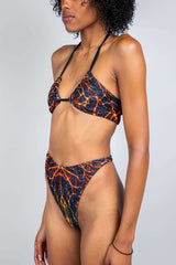 Model wearing Magma Twist Tie Bandeau Top and matching high-waisted rave bikini, featuring a lava-inspired print.